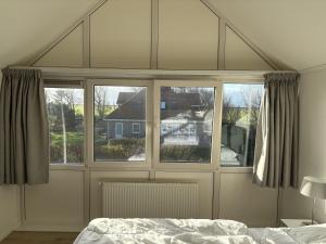 a bedroom with a bed and two windows at Waddenvilla 7 in Hollum