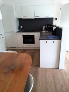 a kitchen with white cabinets and a wooden table at Waddenvilla 7 in Hollum +15 photos