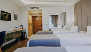 a hotel room with four beds and a television at Sakarya Hotel in Sakarya