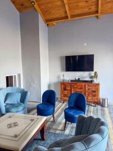 a living room with blue chairs and a tv at Saffron 2 Bedroom Duplex Villa in Mukteshwar