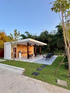 a pavilion with tables and chairs in a park at มนต์จันทรา เฮ้าส์ in Khlong Lan