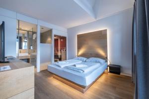 a bedroom with a large white bed and a bathroom at Seehotel Bellevue by keyone in Zell am See +107 photos