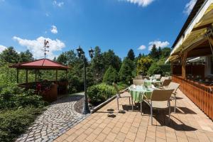 eine Terrasse mit einem Tisch, Stühlen und einem Sonnenschirm in der Unterkunft Parkhotel Tannenhof in Oy-Mittelberg
