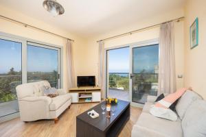 a living room with a couch and a tv and large windows at Villa Stephania in Gaios