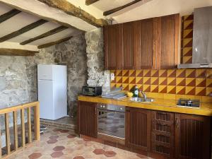 a kitchen with wooden cabinets and a white refrigerator at Mas Costa in Sant Ferriol +52 photos