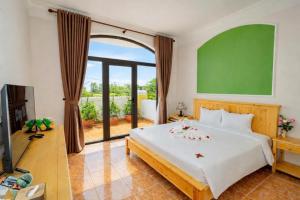 a bedroom with a large bed with a greenboard on the wall at Sea and Sand Hotel in Hoi An