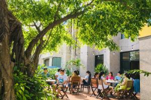 a group of people sitting at tables under a tree at Sea and Sand Hotel in Hoi An +39 photos