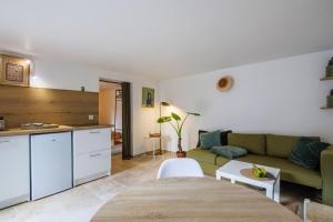 a living room with a green couch and a kitchen at Le Nid in Avignon