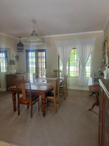 a dining room with a table and chairs and windows at Boschberg Cottage in Somerset East