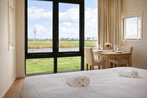 a bedroom with a bed and a table and a large window at Weidesuite bij Leeuwarden. Natuur en 11stedenwater in Weidum