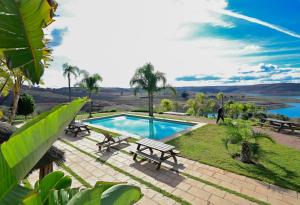 a pool with picnic tables and a view of a river at Lodge du Barrage in Rabat