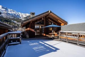 a log cabin with a table and an umbrella at Chalet les trois coeurs in Méribel