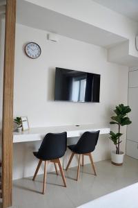 ein Schreibtisch mit zwei Stühlen und einer Uhr an der Wand in der Unterkunft Condo Saga Davao City in Davao City