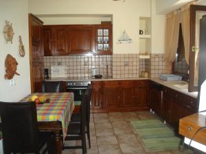 kuchnia z drewnianymi szafkami i stołem z kolorową tkaniną w obiekcie Stelios Seaside House w mieście Lefokastro