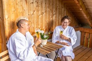 a man and woman sitting at a table in a sauna at Schwarzwaldhotel Schmitz in Todtmoos