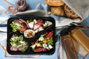 a black container of food with a salad and bread at Villa 33 in Zakopane