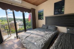 a bedroom with a bed and a balcony with windows at BG Stone Homestay in Mộc Châu