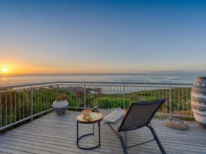 a deck with a view of the ocean at sunset at Walker Bay Villa in Gansbaai +7 photos
