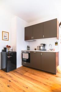 a kitchen with black appliances and a wooden floor at Entspanntes Design-Studio an der Karli in Leipzig