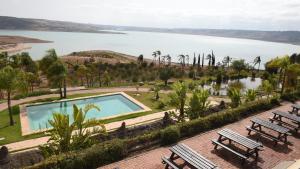a swimming pool next to a body of water at Lodge du Barrage in Rabat