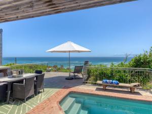 a swimming pool with a table and an umbrella at Walker Bay Villa in Gansbaai