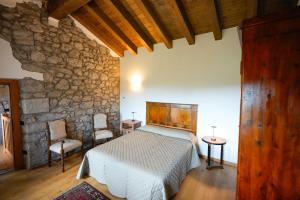 a bedroom with a bed and a stone wall at Villa Borgo Murs in Clauzetto +72 photos