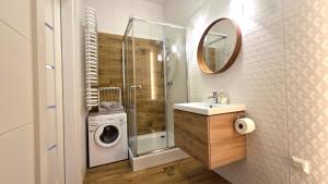a bathroom with a washing machine and a washer at Studio - Apartamenty Parkowe in Gniezno
