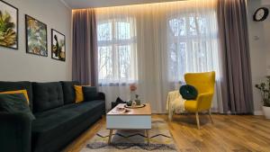 a living room with a green couch and a yellow chair at Studio - Apartamenty Parkowe in Gniezno +12 photos