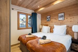 two beds in a hotel room with wooden walls at Appartement Hermine in Les Allues
