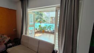 a living room with a couch and a large window at Hideout 2bhk Kharadi Near EON in Pune