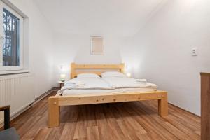 a bed in a room with white walls and wooden floors at Na Samotě u tratě in Nepomuk