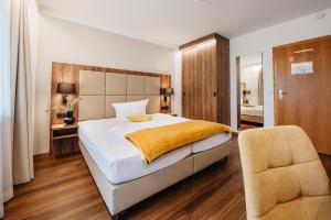 a bedroom with a large bed and a chair at Hotel Lorenz in Bad Füssing