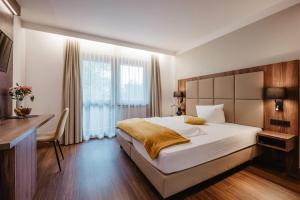 a bedroom with a bed and a desk and a window at Hotel Lorenz in Bad Füssing