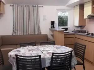 a kitchen with a table and chairs in a room at ZEcamping 3 étoiles piscine chauffée toboggans pet friendly locatif TV 8 pers in Saucède