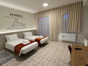 a hotel room with two beds and a table at Pombal City House in Pombal