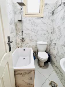 a white bathroom with a toilet and a bath tub at Luxor apartment in Luxor +14 photos