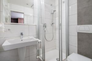 a white bathroom with a sink and a shower at Hotel Lorenz in Bad Füssing
