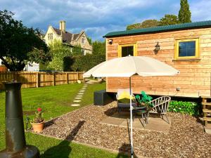 a patio with a table and an umbrella in a yard at Hut in the hall in Bedale