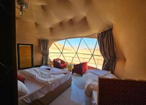 a bedroom with two beds and a large window at Joker camp Wadi Rum in Disah