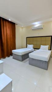 two beds sitting in a room with white floors at Coral Bay Suite Hotel in Khor Fakkan +9 photos