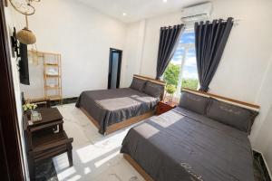 a bedroom with two beds and a window at Cosy 2 Homestay in Hue
