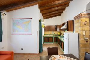 a kitchen with a white refrigerator and a map on the wall at Tri Re e 'na Regina in Cinisi