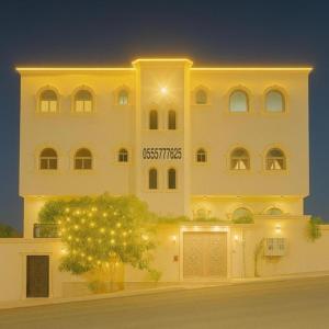 a large white building with a tree in front of it at شقةكبيرة 4 غرف نوم وصالة بلكونه Large apartment with 4 bedrooms, a living room and a balcony in Taif