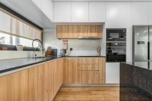 a kitchen with white cabinets and black counter tops at Dune House - Villa With Private Dune and Sea View in Viana do Castelo +45 photos