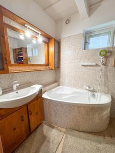 a bathroom with a tub and a sink and a mirror at Sziget Vendégház Parád in Parád +9 photos