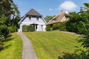 a white house with a grassy yard and a pathway at Strandhaus Gabriella 02 in Ahrenshoop