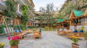 a patio at a hotel with tables and chairs at Purnima Little Italy in Manāli