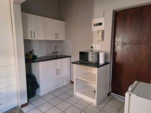 a kitchen with white cabinets and a microwave on a counter at LaBoezma Accommodation in Oudtshoorn
