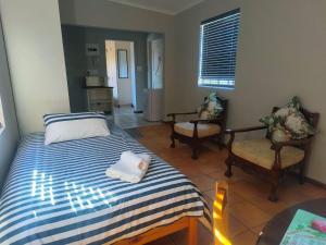 a bedroom with a bed and two chairs and a window at LaBoezma Accommodation in Oudtshoorn
