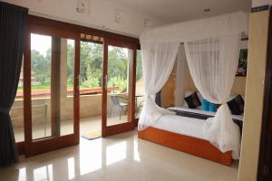a bedroom with a canopy bed and a balcony at Aby Guest House in Sidemen